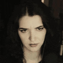 a woman with long dark hair is making a serious face