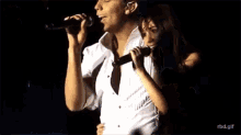 a man and woman singing into microphones on a stage