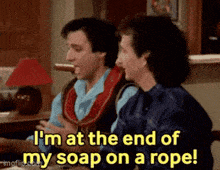 two men are sitting at a table and one of them says i 'm at the end of my soap on a rope .