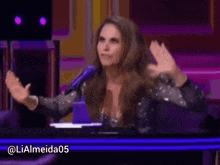 a woman in a sequined dress is sitting at a table with her hands in the air .