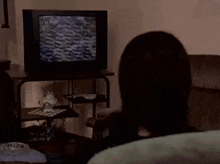 a woman sits in a chair watching a television in a living room