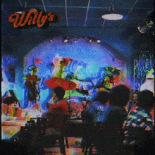 a group of people sit at a table in front of a stage at willy 's