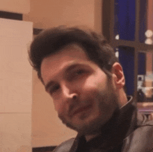 a man with a beard is looking at the camera and smiling .