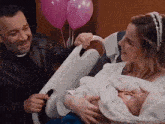 a man and a woman are holding a baby in a hospital bed