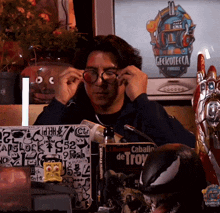a man adjusts his glasses in front of a screen that says geckotecca