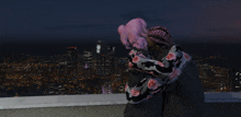 a couple standing on top of a building looking at a city at night