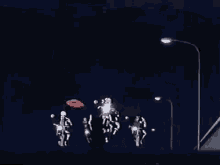a group of people are riding motorcycles down a street at night