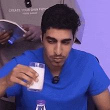 a man in a blue shirt is drinking milk from a glass