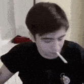 a man in a black shirt is smoking a cigarette while sitting at a table .