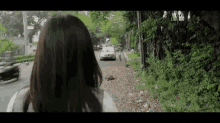a woman is walking down a street looking at a car driving down the street .
