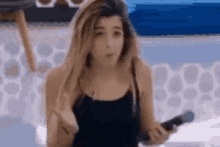 a woman is holding a microphone in her hand and making a funny face .