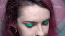 a woman with red hair is wearing green eye shadow