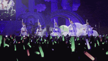 a group of girls are dancing on a stage with green lights in the crowd