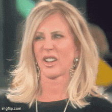 a woman with blonde hair is wearing a black top and earrings