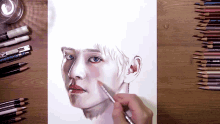 a person is drawing a man 's face with colored pencils on a table