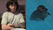 a man with a tattoo on his arm is sitting at a table next to a seal that is swimming in the water .