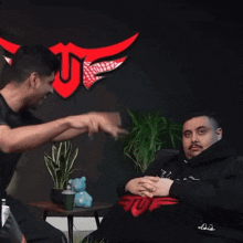 a man pointing at another man who is wearing a hoodie that says tuf on it