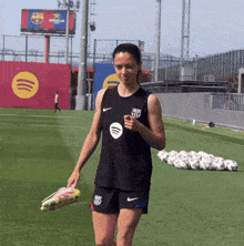 a woman walking on a soccer field wearing a shirt that says ' spotify ' on it