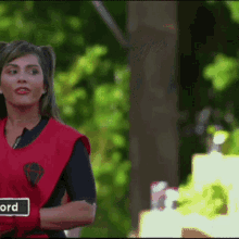 a woman wearing a red vest has a sign on her arm that says ' word '