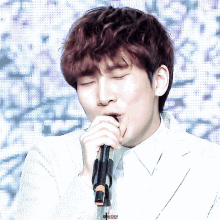a close up of a man singing into a microphone with his eyes closed in front of a pixelated background
