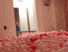 a man is standing in a room filled with red and white balls