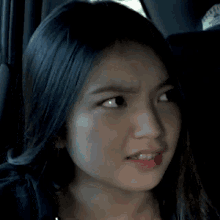 a close up of a woman 's face in a car with a sticker on the back seat that says " california "