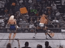 a woman in a blue dress is standing next to a man in a wrestling ring holding a guitar .