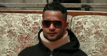 a man wearing sunglasses and a neck brace sitting on a couch