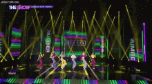 a group of people are dancing on a stage with a sign that says the show