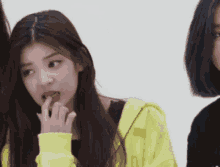 a girl wearing a yellow hoodie is biting her finger