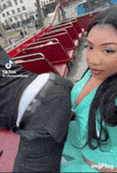 a woman in a green top is standing next to a man in a suit on a red bus .