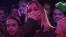 a woman is covering her face with her hand in a crowd of people .