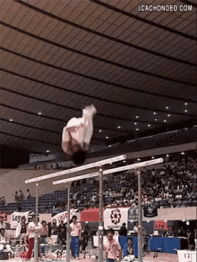 a gymnast is doing a trick on a pair of parallel bars .