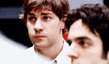 two men are standing next to each other looking at something .