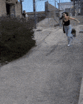 a woman in a black tank top is running down the street