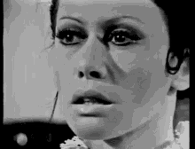 a black and white photo of a woman 's face with her mouth open .