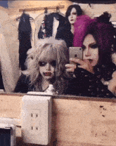 a woman taking a picture of herself in a mirror with a phone