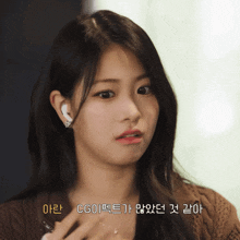 a woman wearing a brown sweater and white ear buds says " cg "