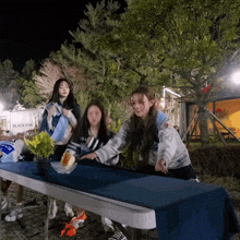 a group of girls are gathered around a table with a sign that says black yak in the background