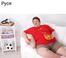 a man sitting on a couch eating chips and drinking beer