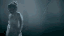 a statue of a woman in a white dress is standing in the dark .
