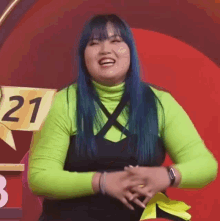 a woman with blue hair is wearing a neon green turtleneck and a black top .