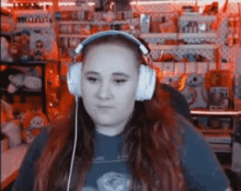 a woman wearing headphones is sitting in front of a shelf .