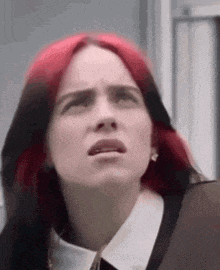 billie eilish has red hair and is wearing a white collared shirt and tie .