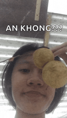 a person holding a potato chip in front of their eye with the caption " an khong " above them