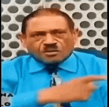 a man wearing a blue shirt and tie is pointing