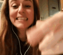 a woman wearing headphones is making a funny face while holding something in her hand .