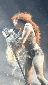 a woman with red hair is singing into a microphone on a stage