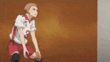 a volleyball player is standing in front of a wall and looking up .