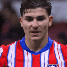 a close up of a man wearing a red and white striped shirt with a blue collar